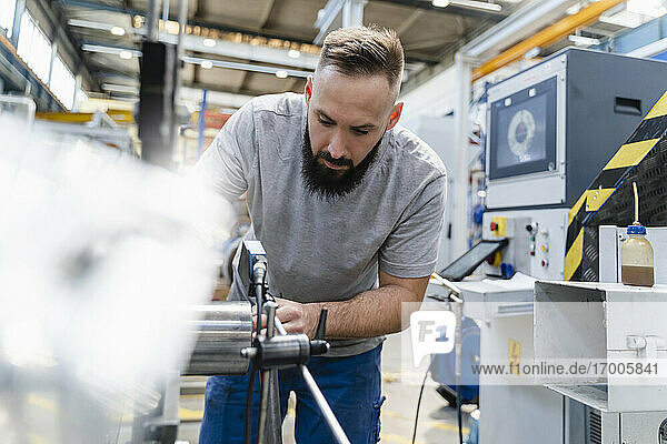 Bearded male technician analyzing machine in industrial factory