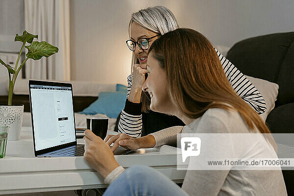 Frauen beim Online-Einkauf am Laptop  während sie zu Hause sitzen