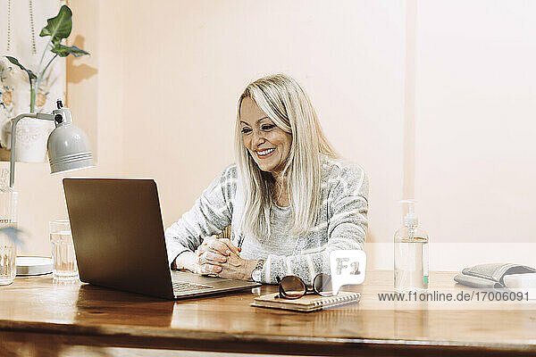 Glückliche Seniorin  die zu Hause eine Online-Beratung über ihren Laptop in Anspruch nimmt