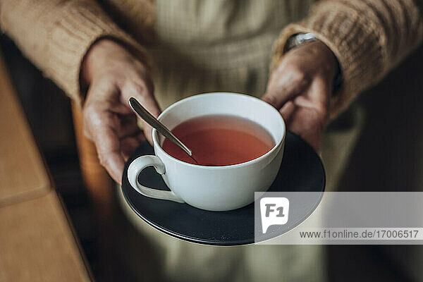 Ältere Frau hält eine Tasse Tee in den Händen