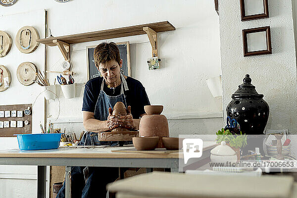 Ältere Künstlerin  die in einem Keramikladen aus braunem Ton töpfert