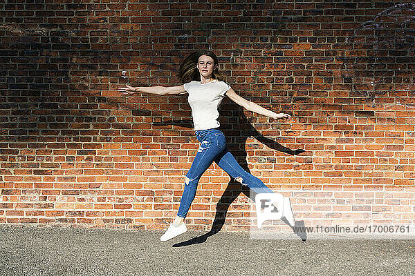 Agile junge Frau springt vor eine Mauer