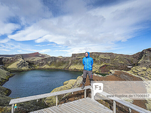 Adventurous man standing on railing of bridge against sky  Lakagigar  Iceland