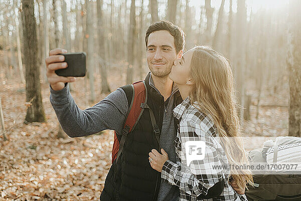 Young couple taking smart phone selfie during autumn hike
