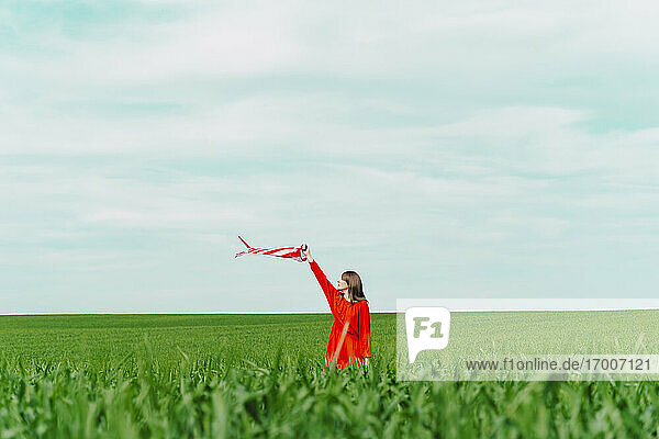 Woman wearing red dress standing on a field holding windsock
