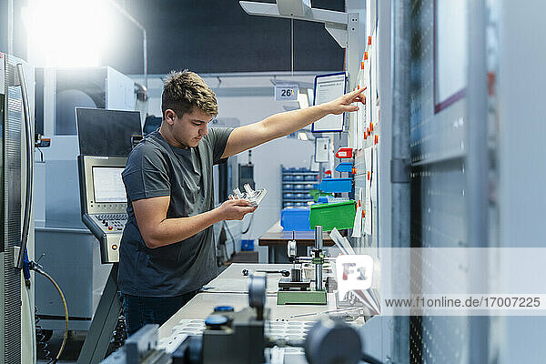 Young engineer pointing toward whiteboard while working at industry