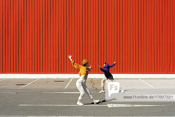 Junger Mann und Frau spielen vor einer roten Wand