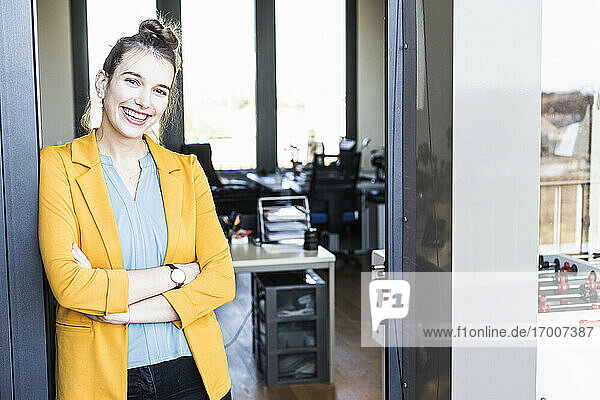 Young businesswoman smiling while standing at entrance in office