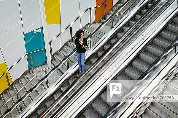 Geschäftsfrau am Telefon stehend auf Rolltreppe