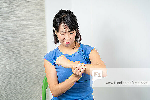 Asiatische Frau mit Schmerzen im Handgelenk