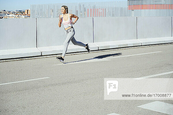 Sportswoman running on road during sunny day