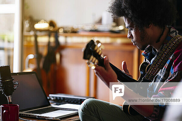 Afro male musician practicing guitar at home