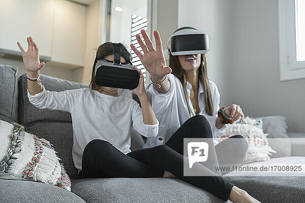 Tochter und Mutter machen eine Stop-Geste bei der Nutzung der virtuellen Realität im Wohnzimmer