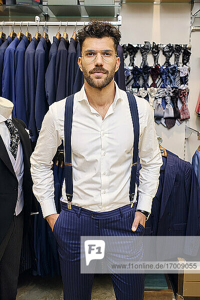 Portrait of customer in white shirt and blue suspenders in tailors boutique