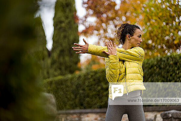 Mittlere erwachsene Frau streckt ihre Hand aus  während sie im Park steht