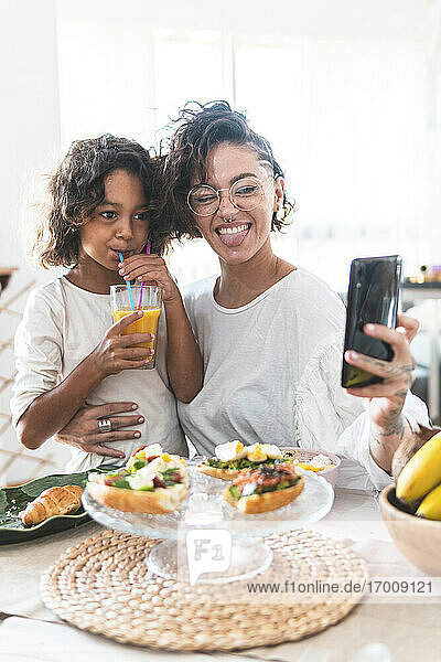 Mutter und Tochter machen ein Selfie beim Frühstück