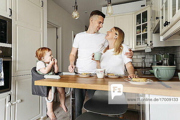 Glückliche Familie mit kleiner Tochter am Küchentisch