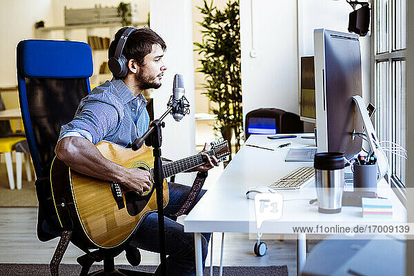Musiker singt beim Gitarrenspiel im Aufnahmestudio