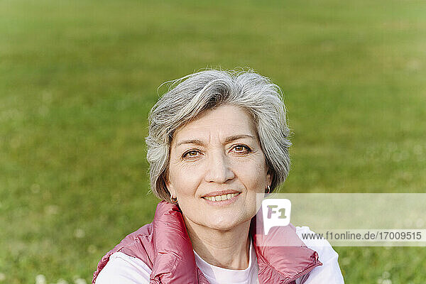 Lächelnde reife Frau im öffentlichen Park an einem sonnigen Tag