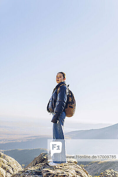 Weiblicher Wanderer mit Rucksack auf dem Gipfel eines Berges gegen den klaren Himmel