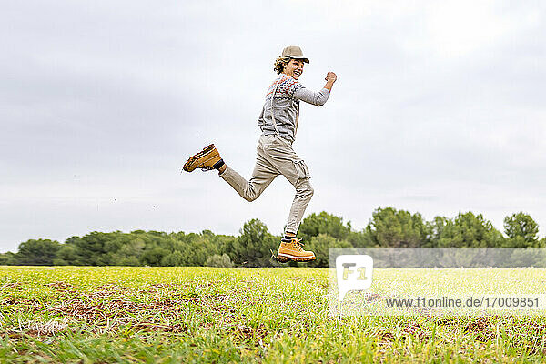 Young man jumping and posing mid-air in grassy field
