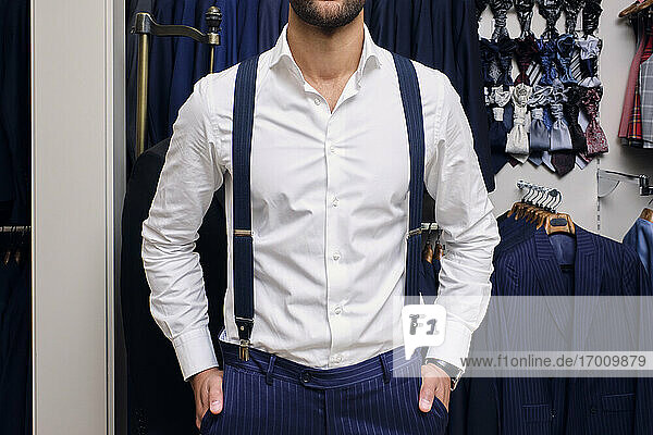 Customer in white shirt and blue suspenders in tailors boutique