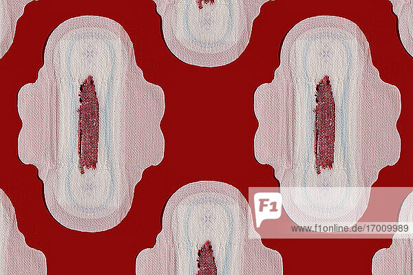 Muster von blutbefleckten Damenbinden vor rotem Hintergrund