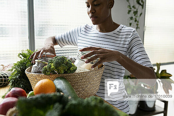 Frau packt Korb mit frischen Bio-Lebensmitteln aus