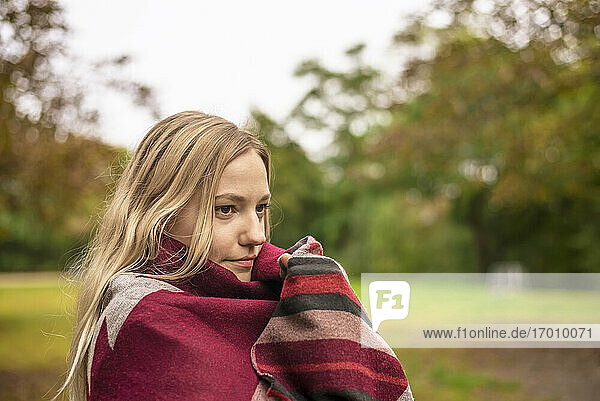 Young woman wrapped in scarf at park during autumn