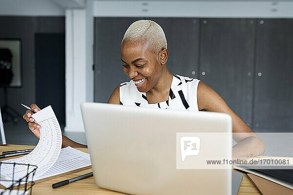 Lächelnde Geschäftsfrau  die in einem modernen Büro arbeitet und einen Laptop benutzt