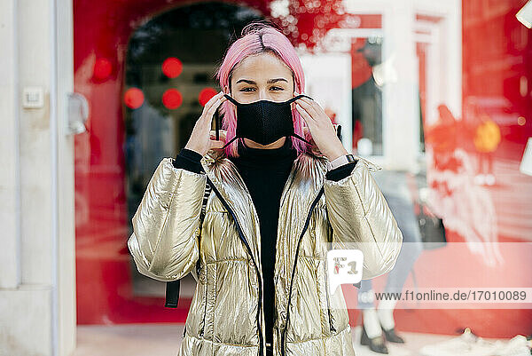 Frau mit rosa Haaren trägt eine Gesichtsmaske  während sie im Freien steht