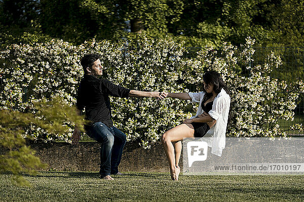 Heterosexuelles Paar  das tanzt  während es die Hand über Gras im Hinterhof hält