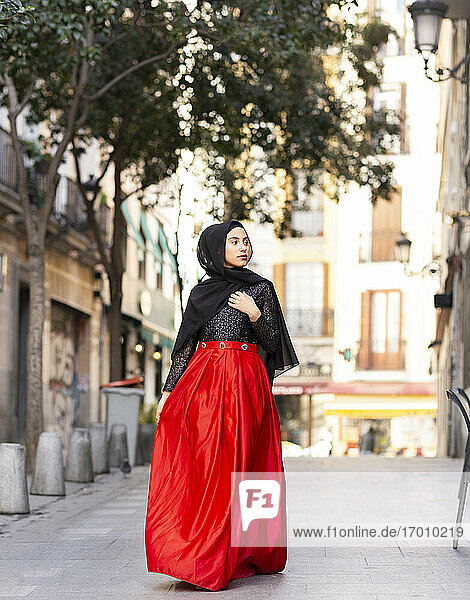 Porträt einer jungen Frau mit Hidschab und langem Rock  die auf dem Bürgersteig geht