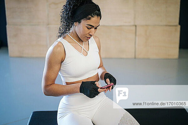 Sportlerin benutzt Mobiltelefon im Fitnessstudio