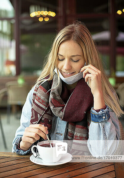 Junge Frau mit Tee in einem Café während der COVID-19