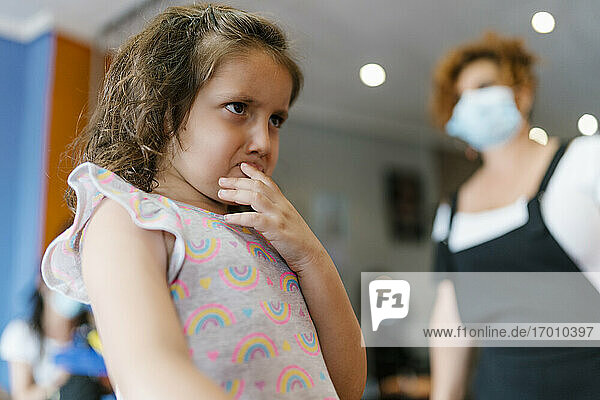 Aufgeregtes Mädchen  das den Friseur im Friseursalon während der Pandemie wegschaut