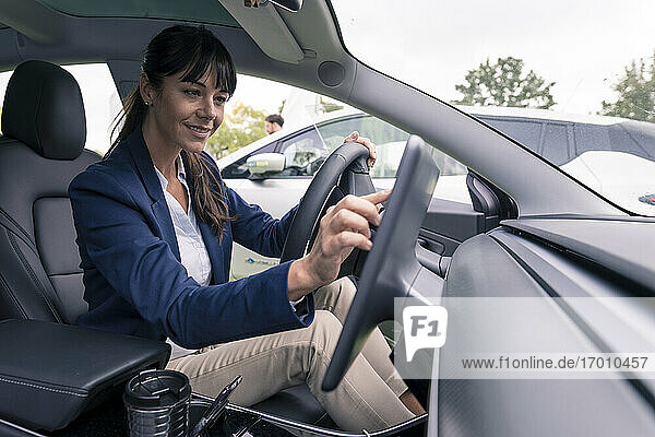 Lächelnde Unternehmerin  die im Auto sitzend durch ein Gerät navigiert