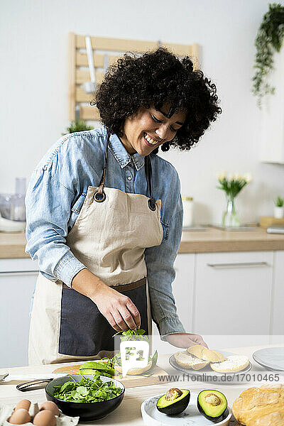 Porträt einer jungen Frau  die in der Küche vegane Sandwiches zubereitet