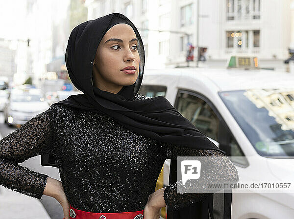 Porträt einer jungen schönen Frau mit schwarzem Hidschab  die auf der Straße posiert
