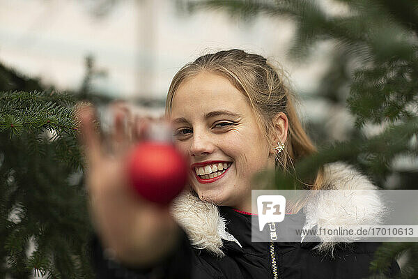 Glückliche junge Frau zeigt Weihnachtsschmuck während der Feiertage