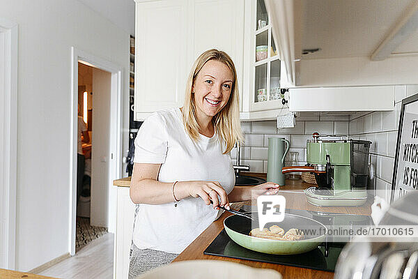 Porträt einer lächelnden Frau beim Kochen