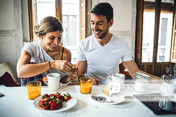 Glückliches junges Paar sitzt am Tisch und frühstückt zu Hause