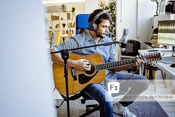 Gitarrist spielt Gitarre und sitzt am Mikrofonständer im Aufnahmestudio