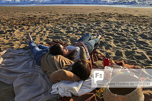 Paar liegt auf einer Decke und ruht sich am Strand aus