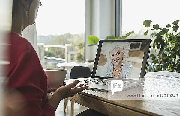 Ältere Frau lächelt während eines Videogesprächs auf dem Laptop-Bildschirm