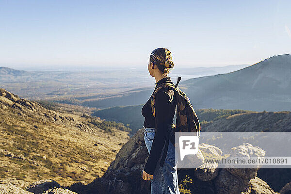 Female hiker with backpack looking at view while standing on top of mountain
