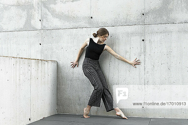 Tänzerin in schwarzer gestreifter Hose vor einer Betonwand