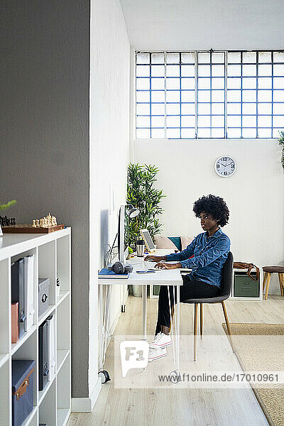Frau arbeitet am Computer  während sie zu Hause im Büro sitzt