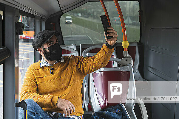 Businessman taking selfie with mask on face while commuting in bus