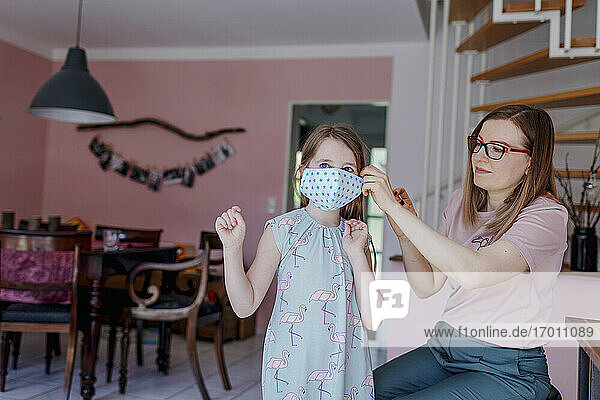 Mother wearing mask to daughter at home during COVID-19